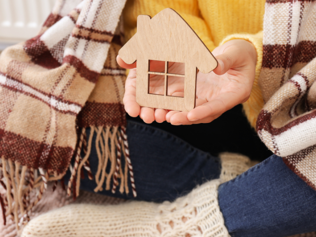 Person Holding a House Sign with blanket around them