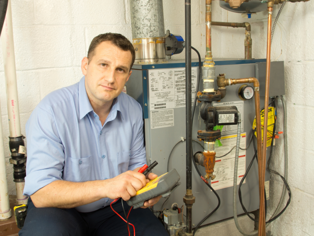 Technician next to natural gas furnace